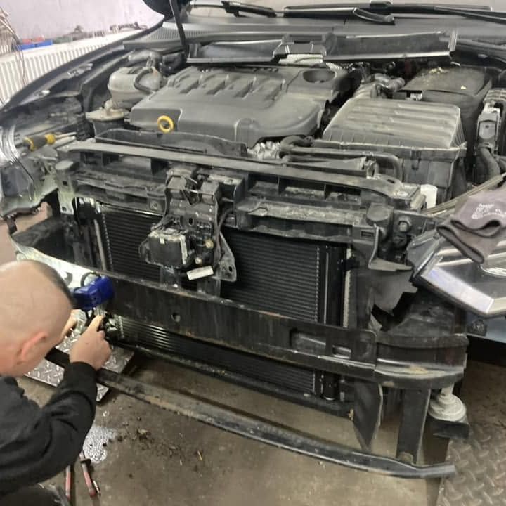 Mechanik pracuje na prednej časti auta so zloženým nárazníkom